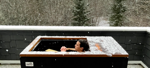 Man cold plunging outdoors in the snow using a RENU Therapy cold plunge tank